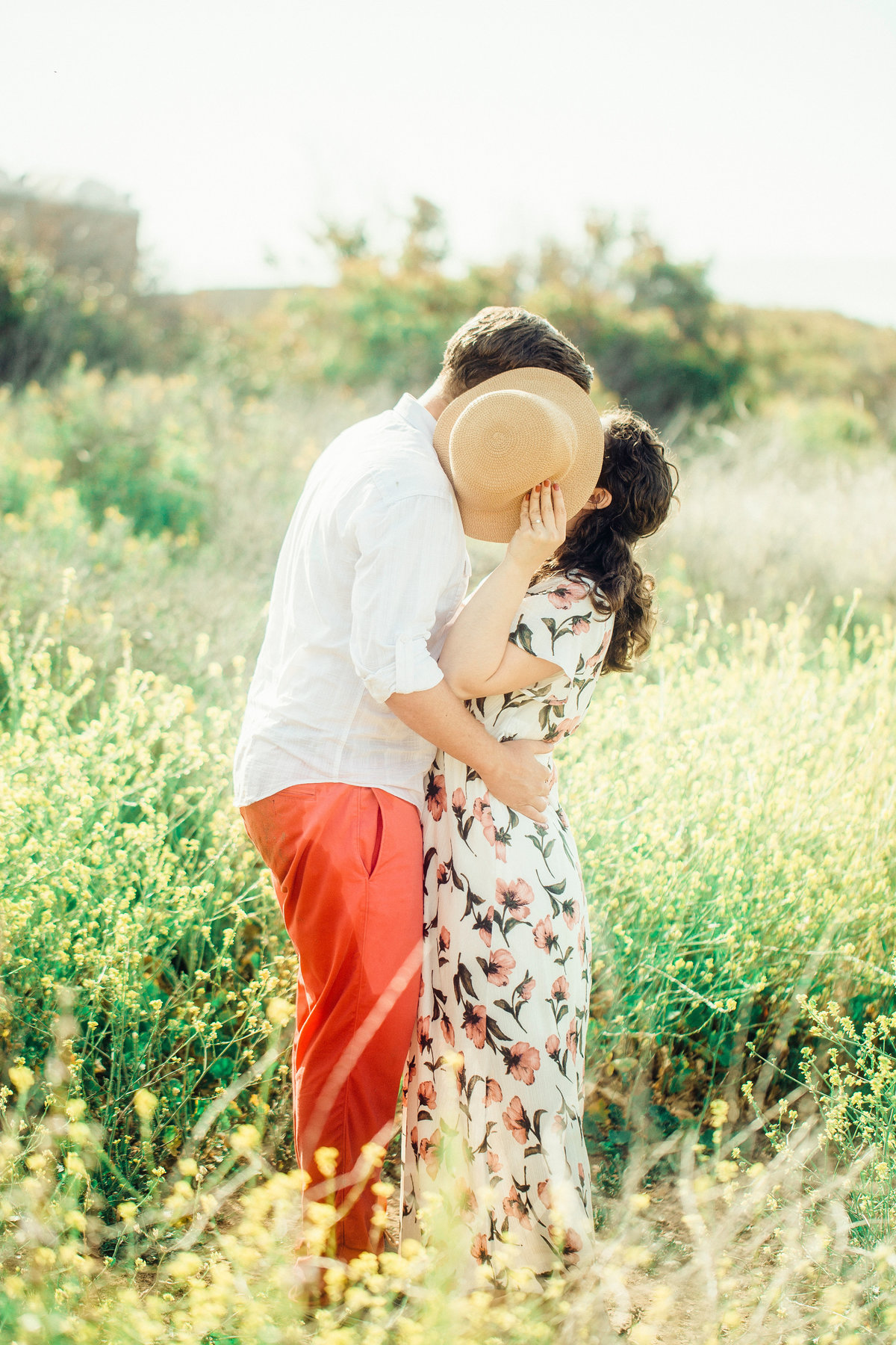 Engagement Photograph Of Woman Holding Up a Hat While Kissing a an Los Angeles