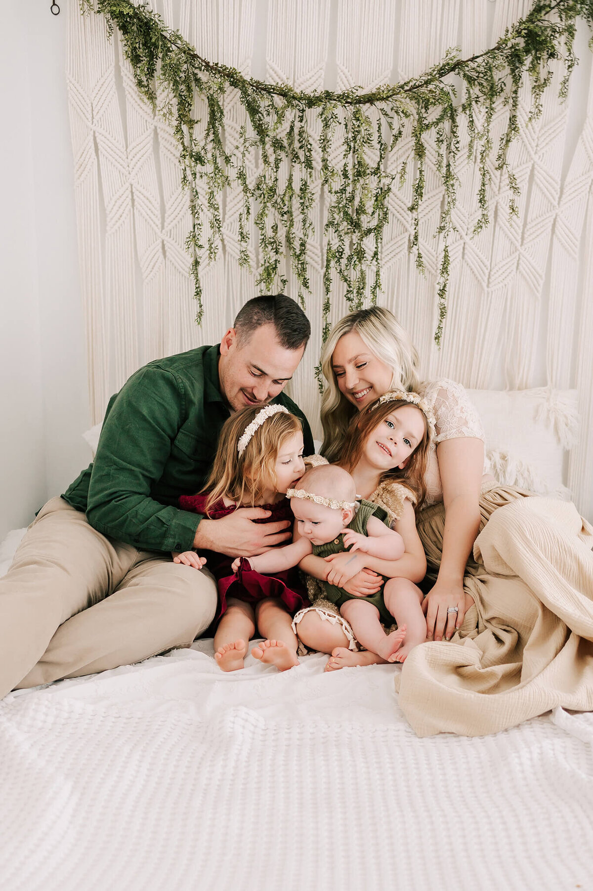 parents hugging kids in bed in family photography studio in Springfield MO