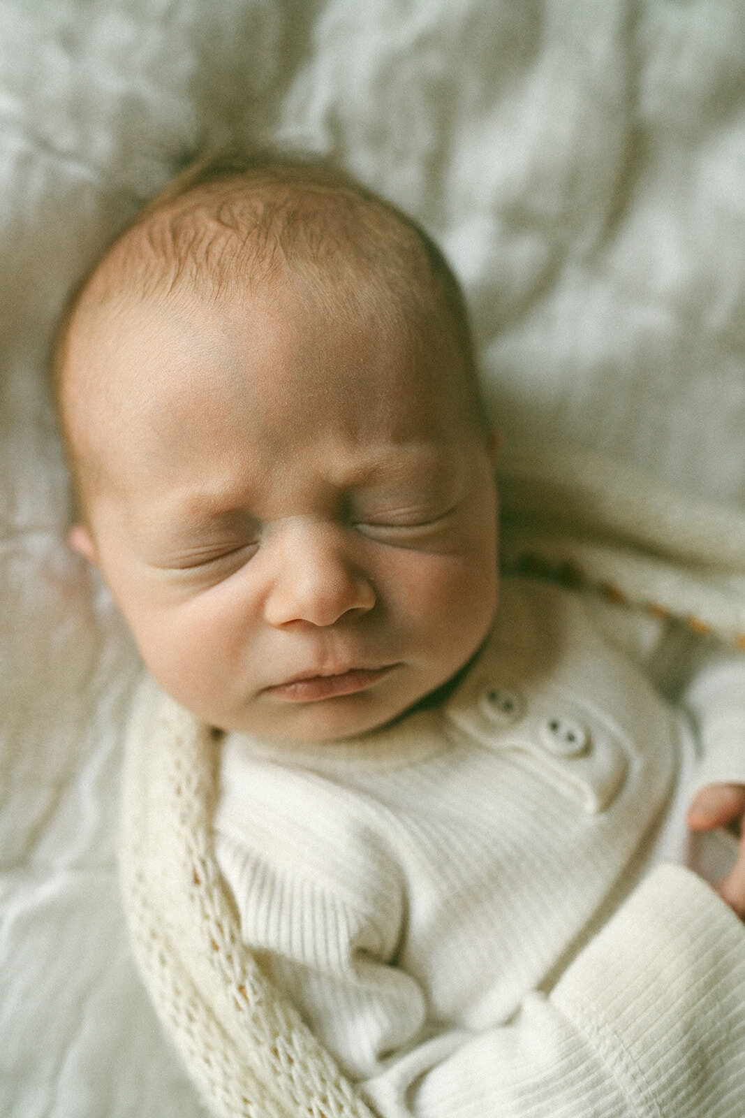 Swaddled newborn baby sleeping peacefully during a lifestyle newborn photography session at home