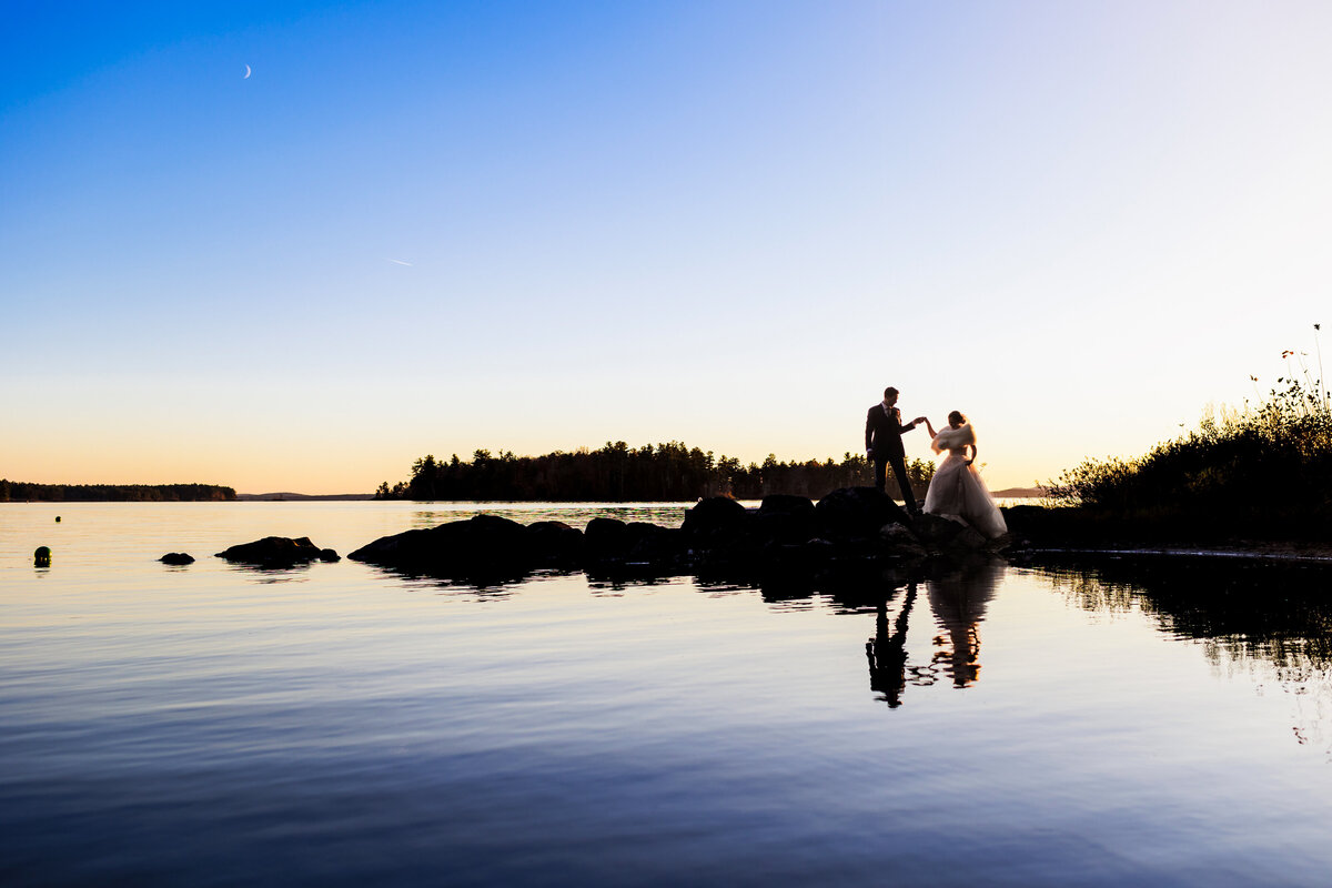 Newlyweds silhouetted with the water at Migis Lodge in maine