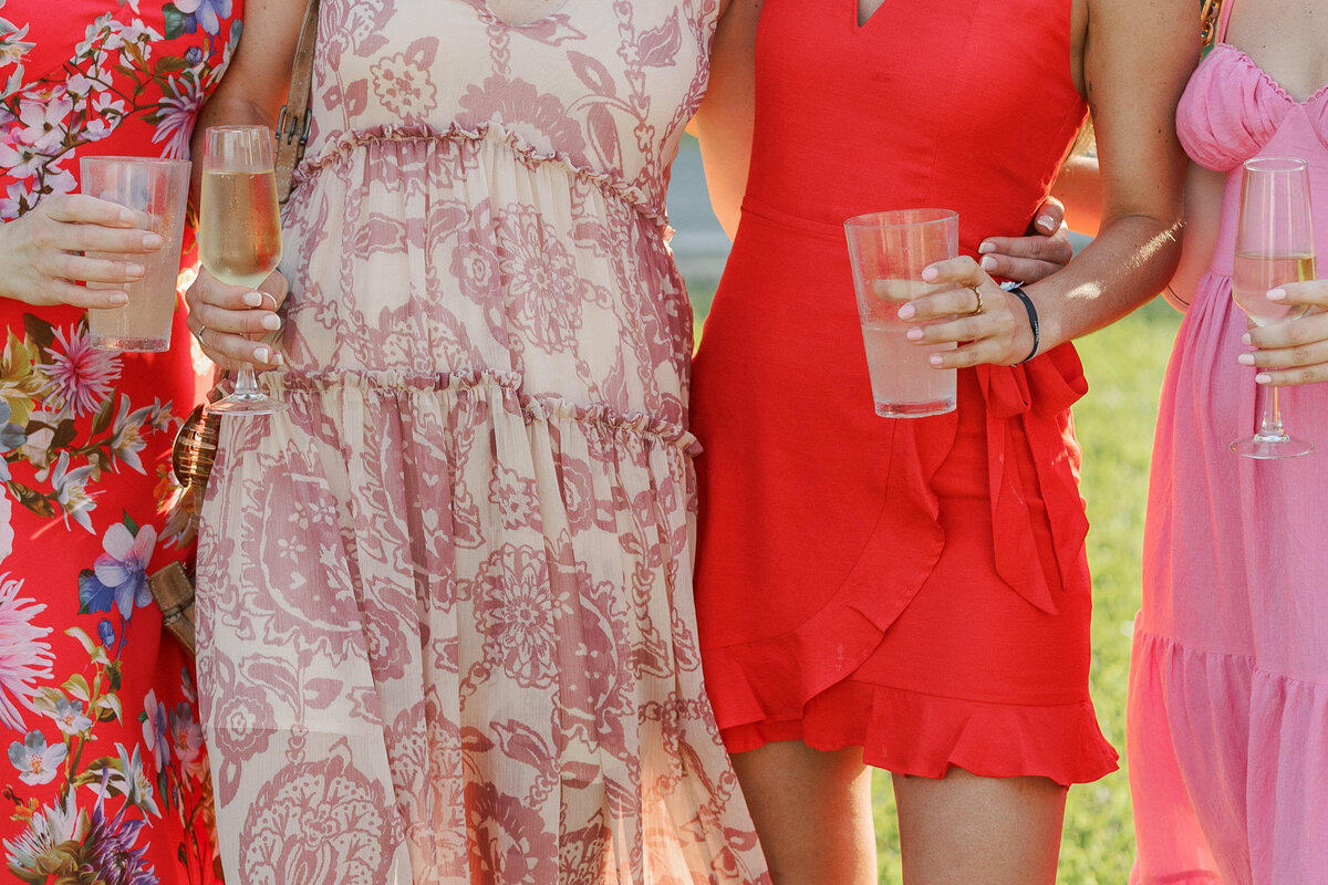 Guests hold drinks in colorful dresses at a Cancun wedding captured by a Philadelphia wedding photographer.