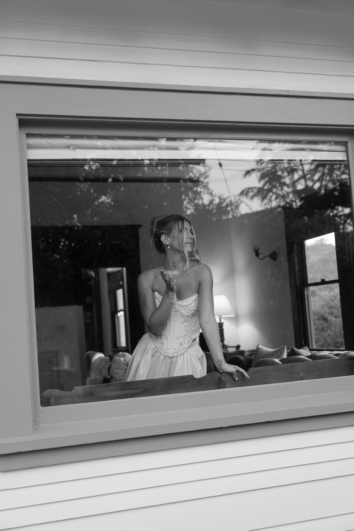 Candid shot of the bride getting ready, looking out a window at her Southern California wedding venue in La Jolla, capturing a moment of anticipation.