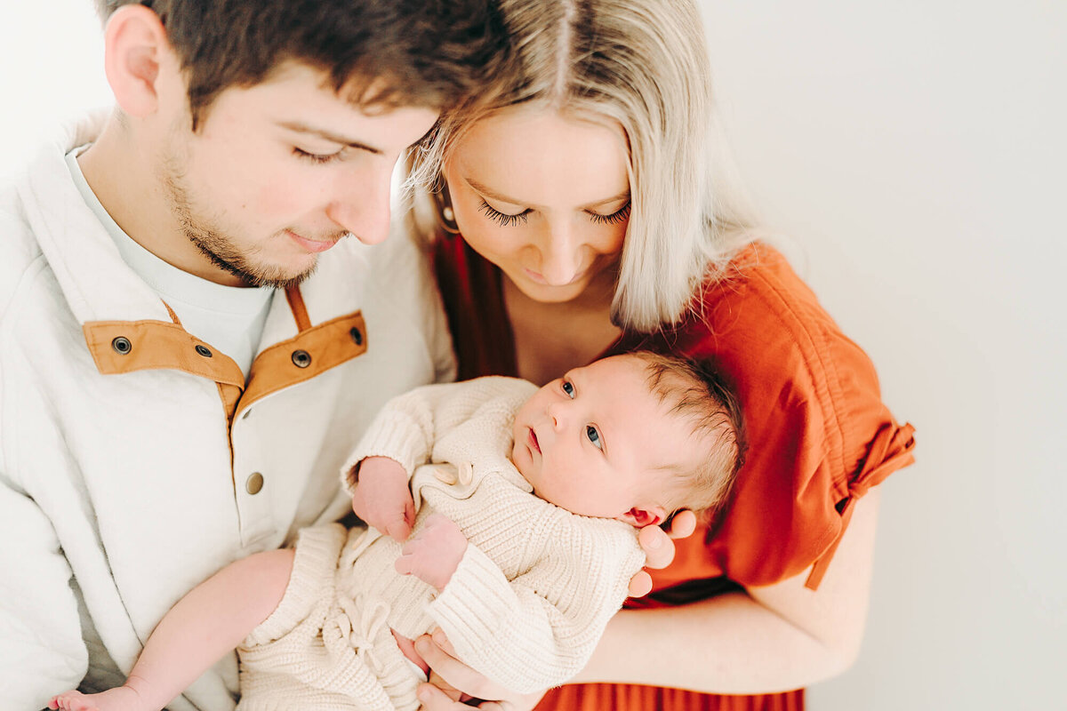 parents snuggle and look at baby during newborn session in jackson missouri