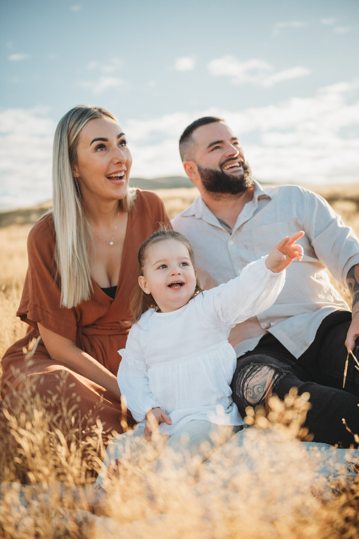 a fmaily posing in the grass during their queenstown family photography session captured by Bie