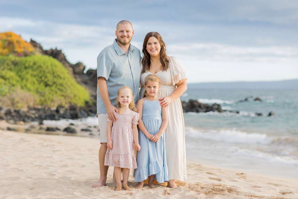 Photo of mom and dad and two little girls standing on the beach in Maui, Hawaii