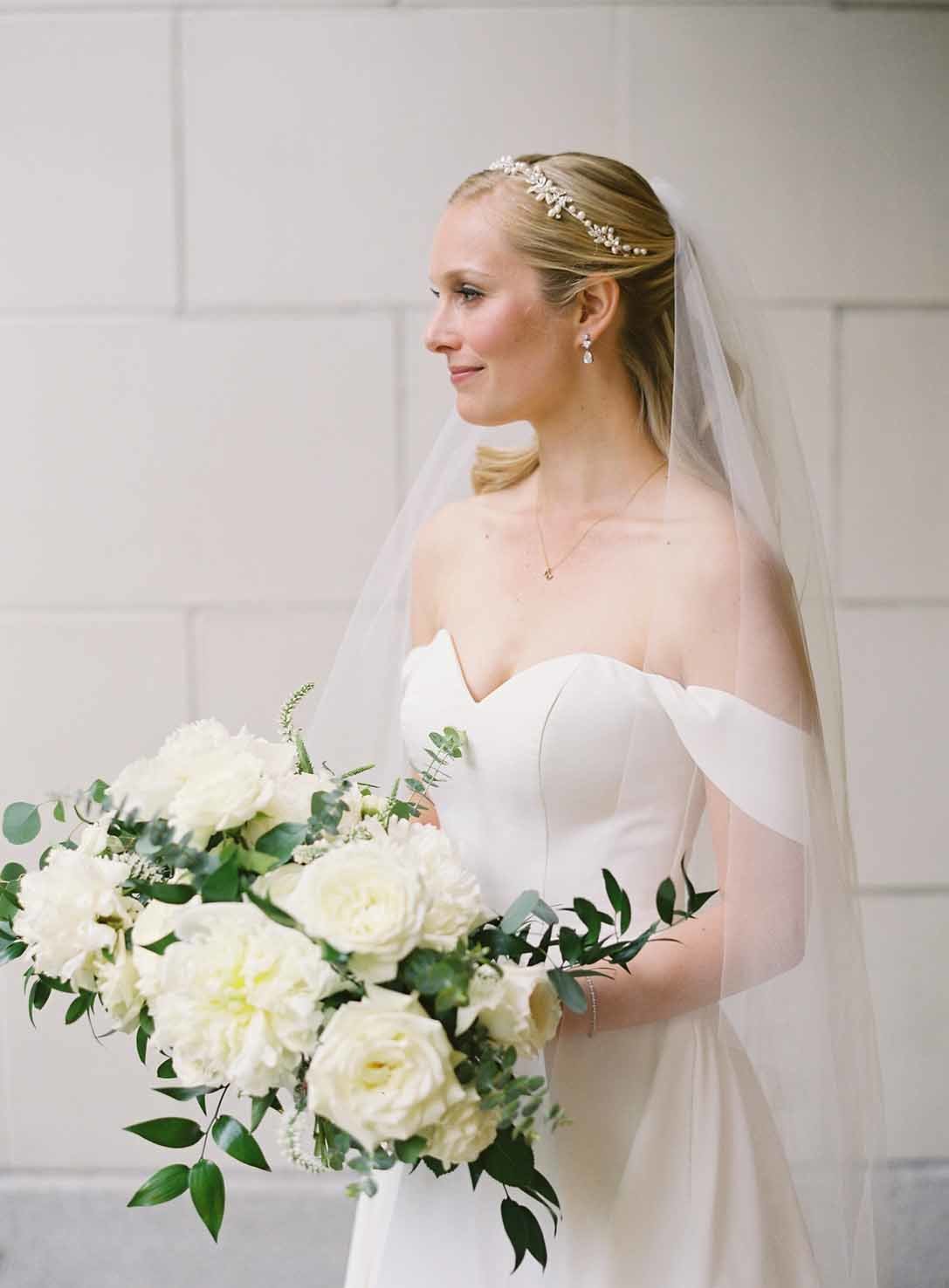 bride holding a large bridal bouquet of white garden roses