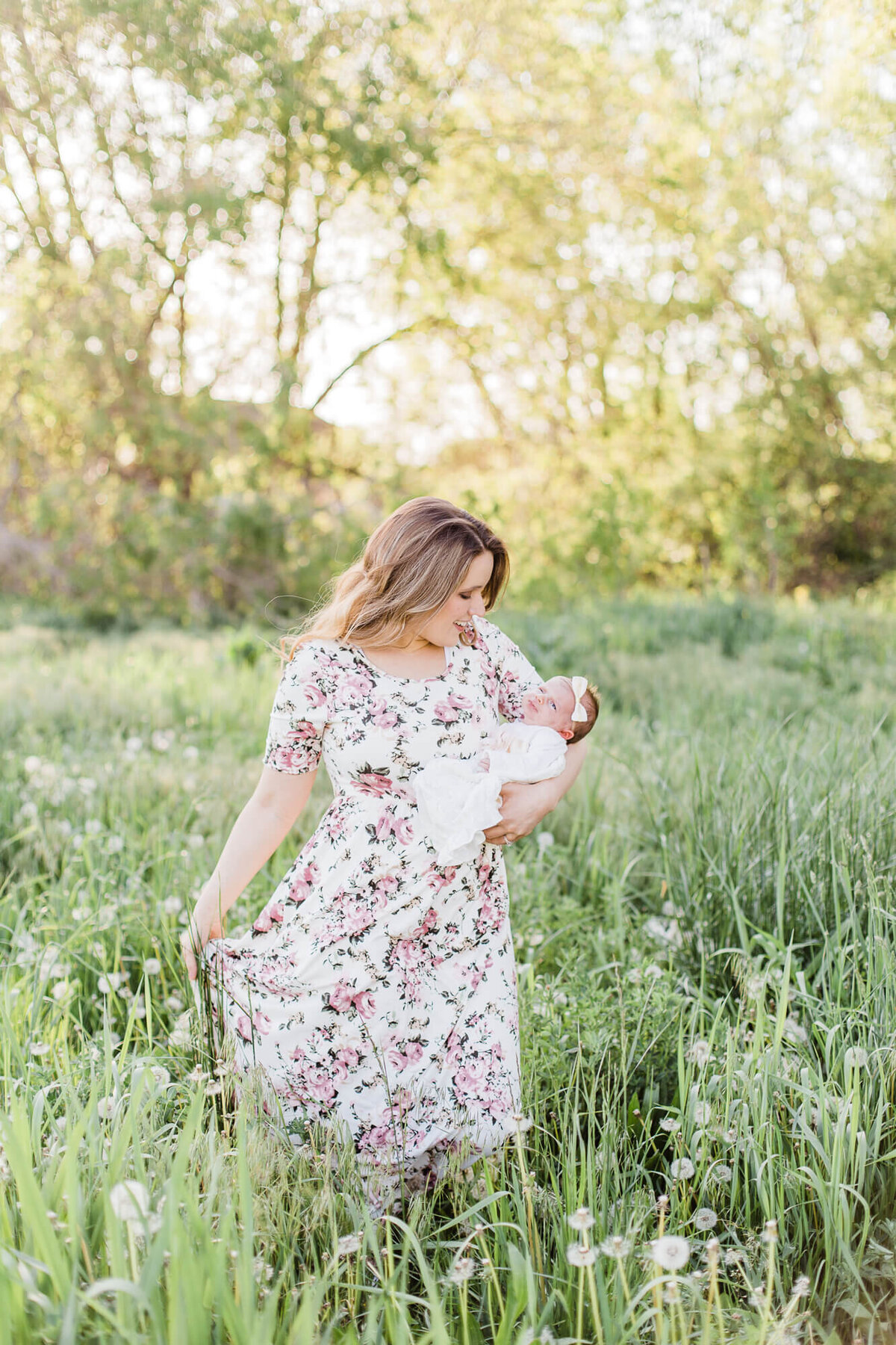 woman in a flowered dress holding a baby in a field of flowers