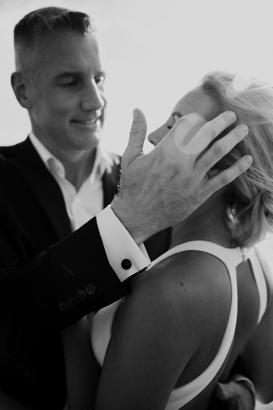 Groom smiles at bride and strokes her hair