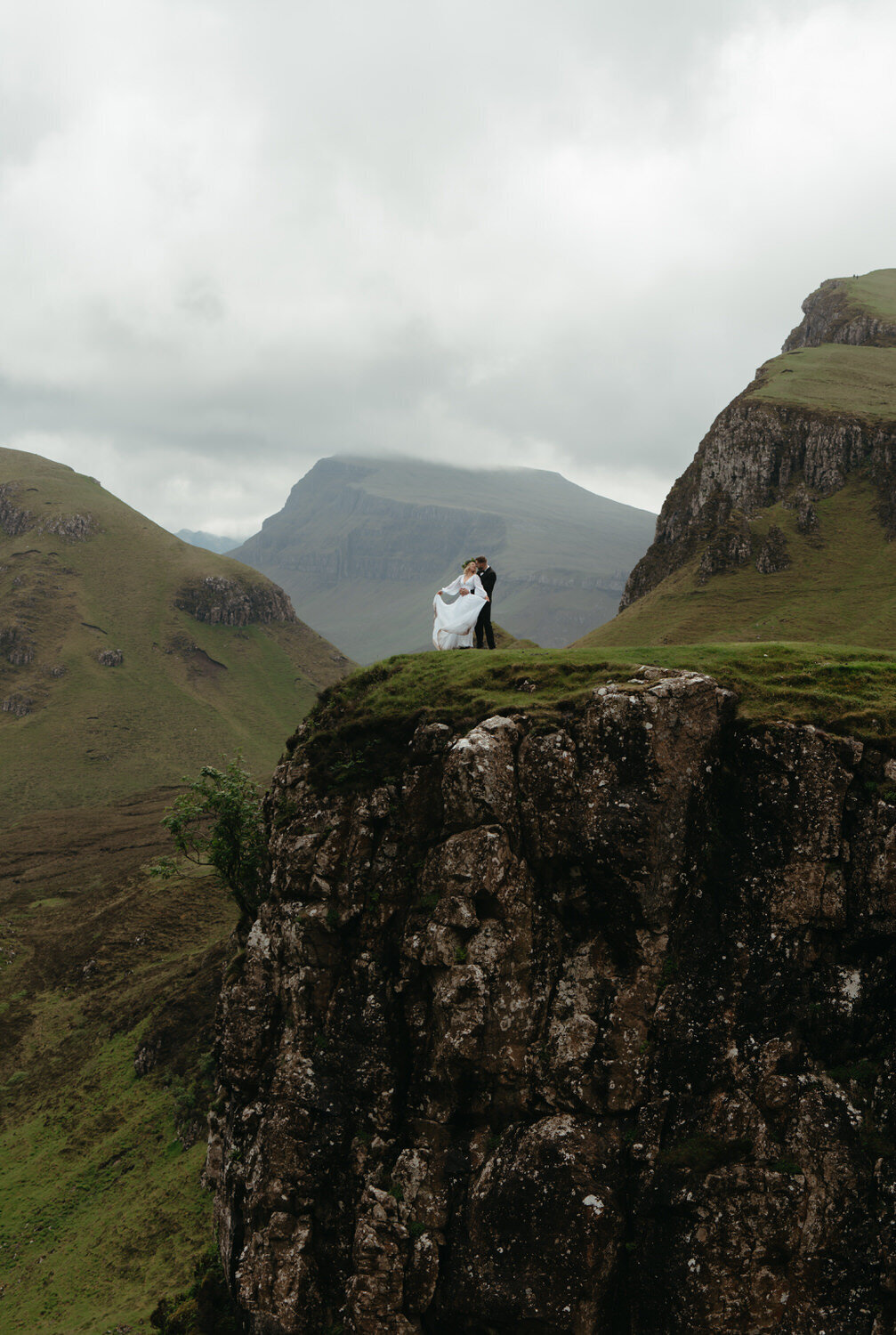 Hiking wedding in Scotland with couple hugging on top of a mountain