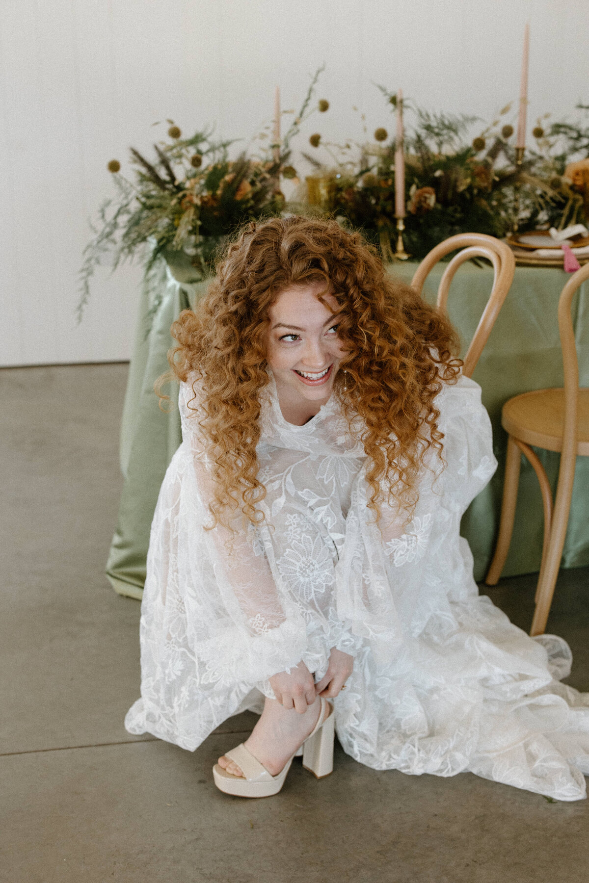 The bride getting ready for her wedding while she puts her heels on