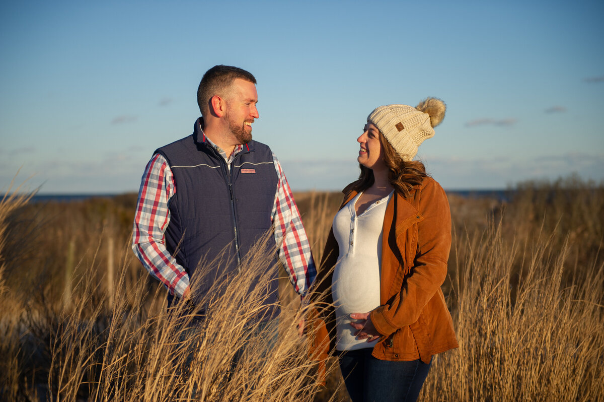 maternity couple in tall grasses on beach in winter