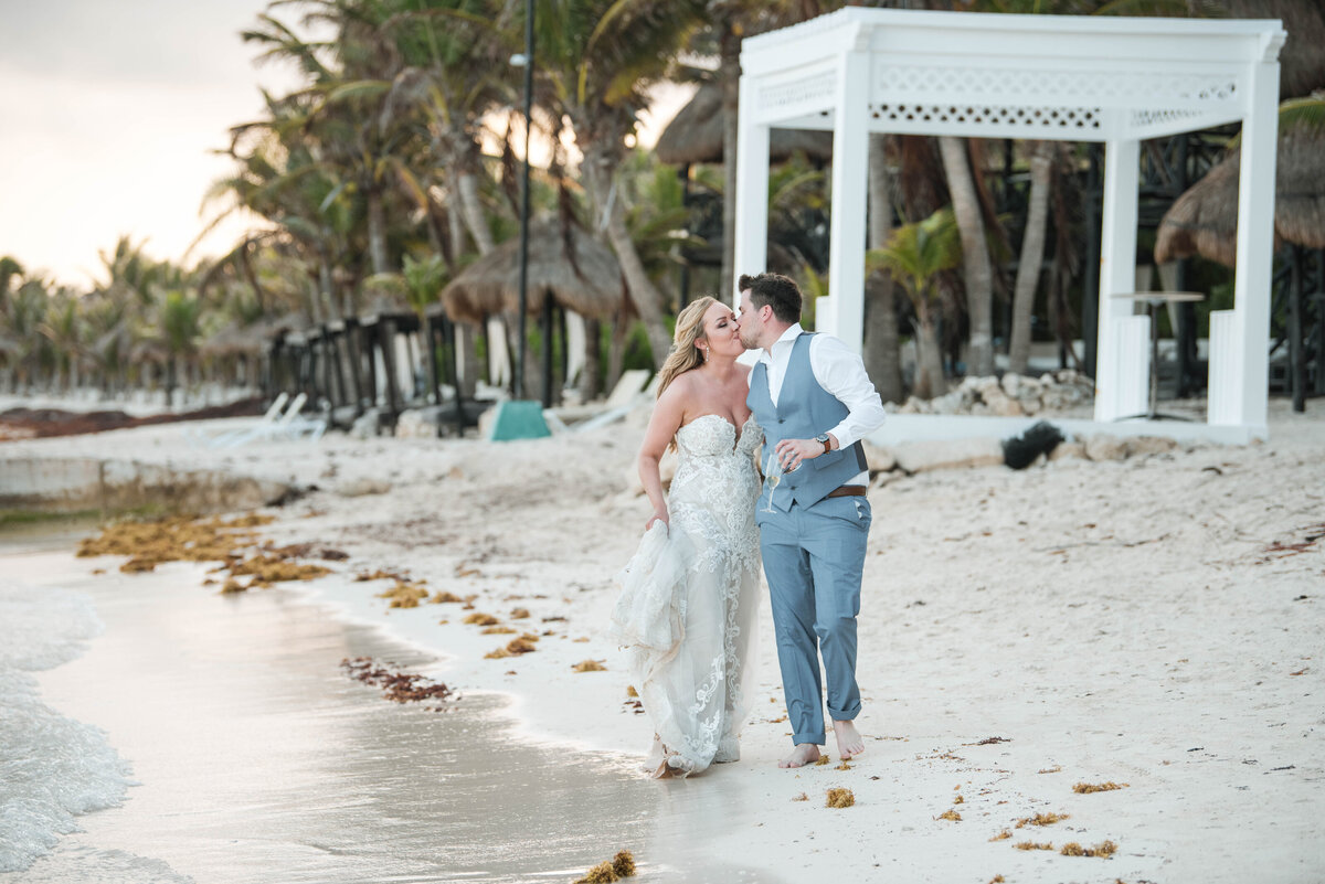 a newly married couple walk the beach in Cancun