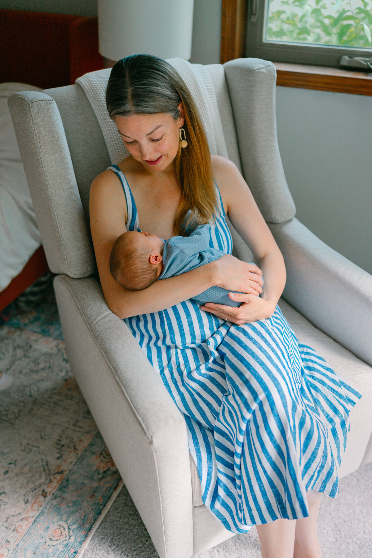 A parent sitting in a chair holding a newborn