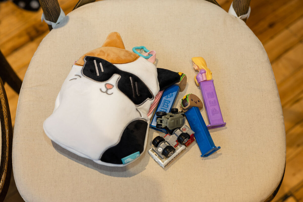 A stuffed cat wearing sunglasses is surrounded by toys and a pez dispenser