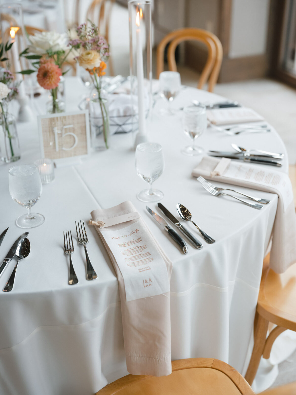 custom calligraphy wedding menu with flatware placed on a napkin on a wedding tablesetting with florals and a table number representing full service design and calligraphy by Life in Letters.