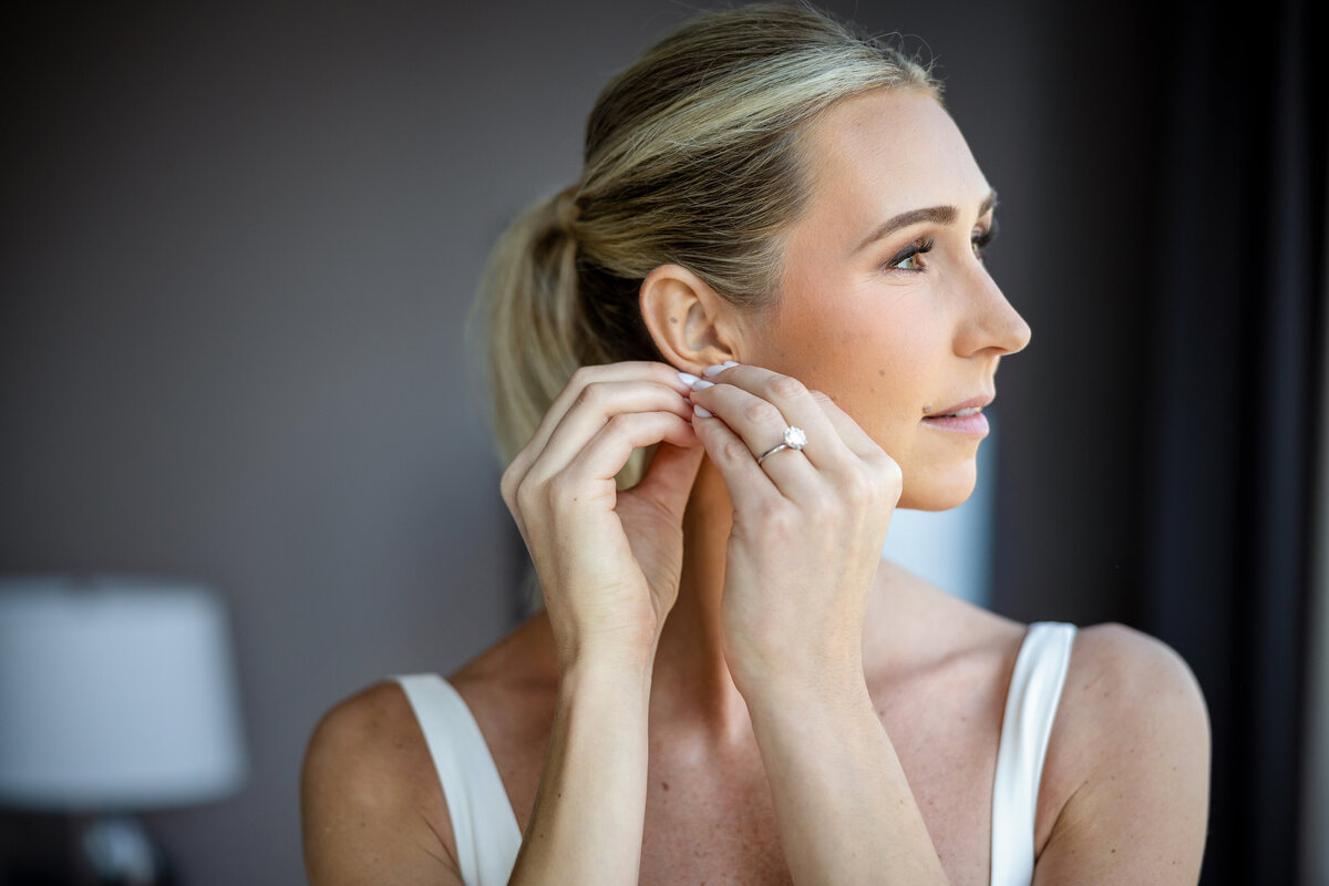 Bride with pony tail in natural light near the window getting ready for the wedding