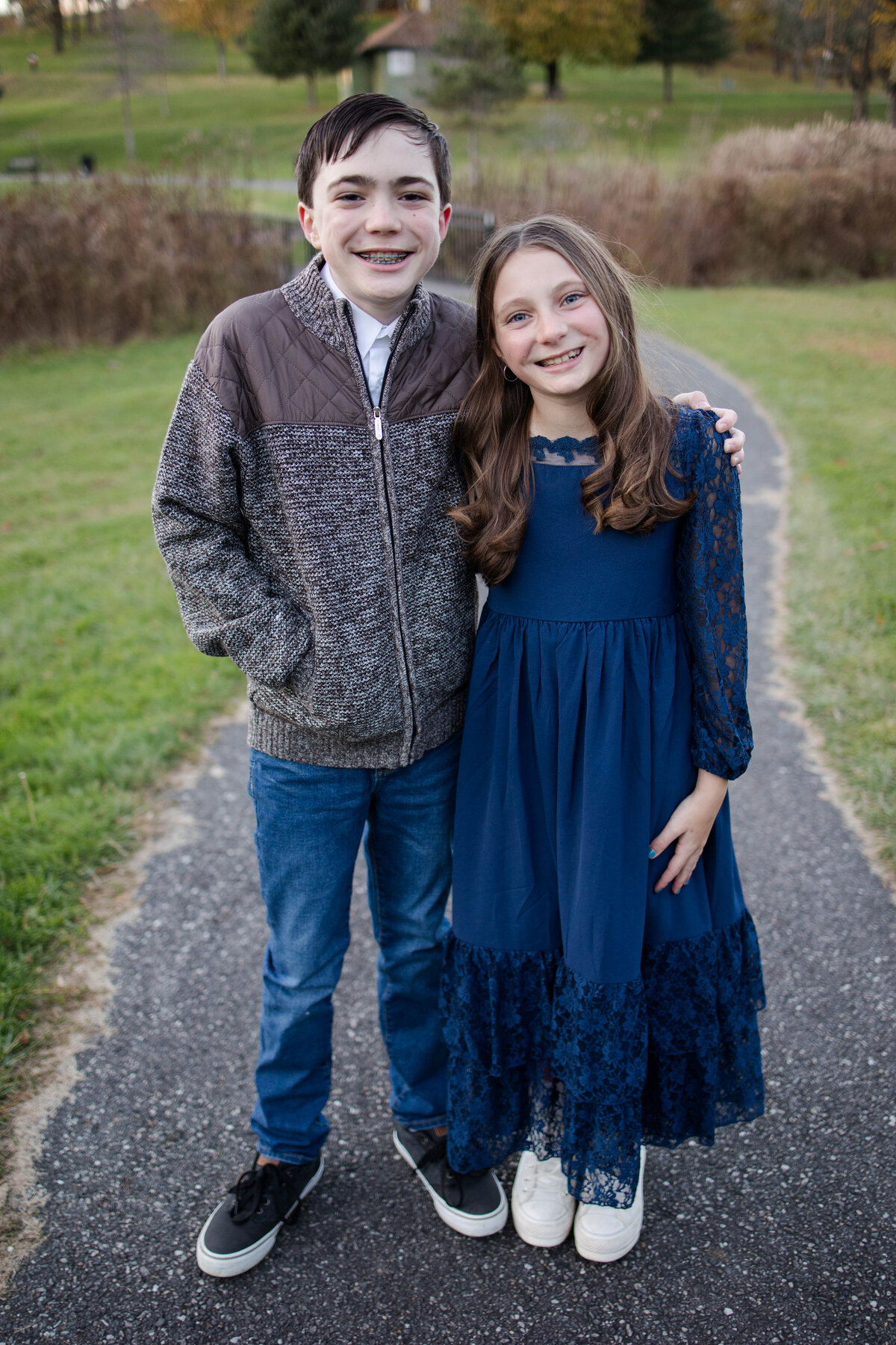 siblings hugging and smiling in the fall on a small path in worcester mass