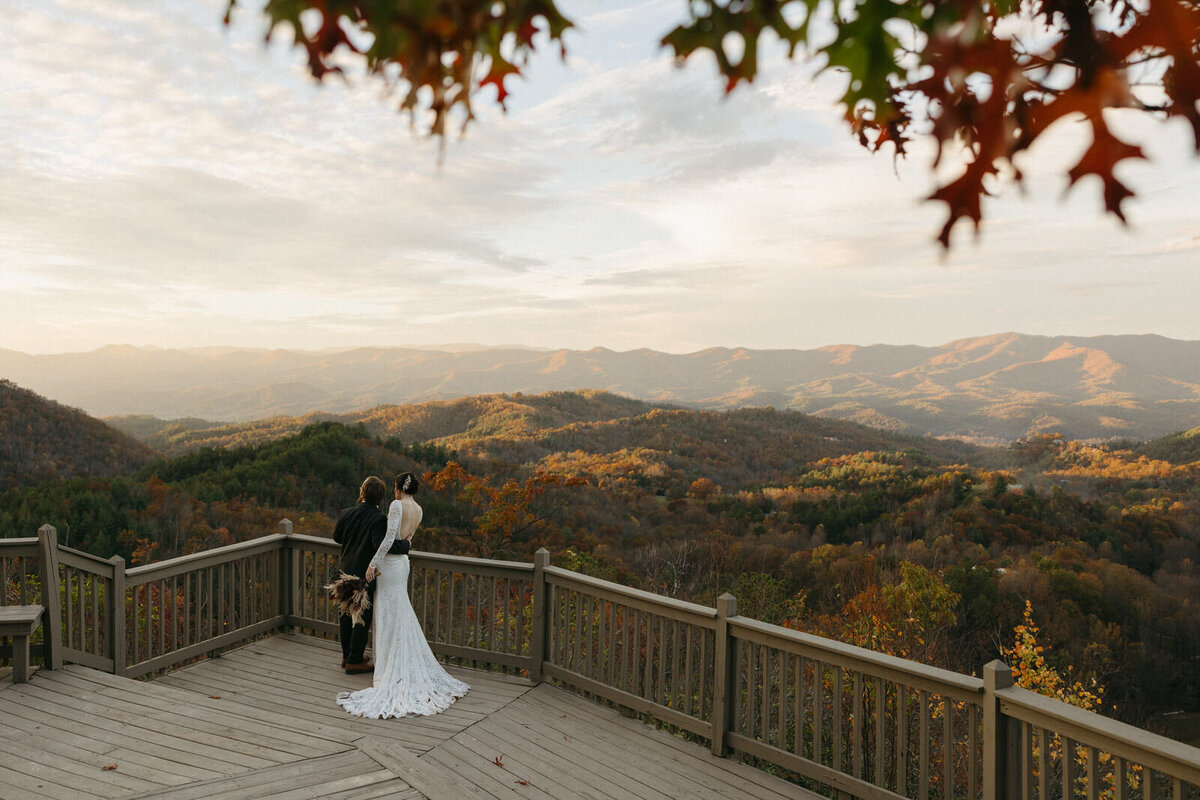 Bride and groom overlooking the Blue Ridge Mountains in North Carolina while the golden sunset lights up the fall leaves changing for their wedding day, by Andrea-Marie Photography