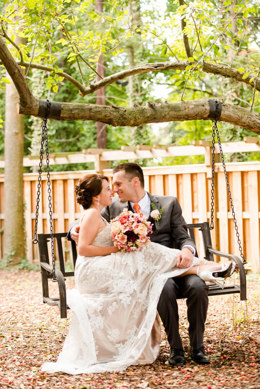 married couple posing on a swing in the back side of the Hyeholde restaurant