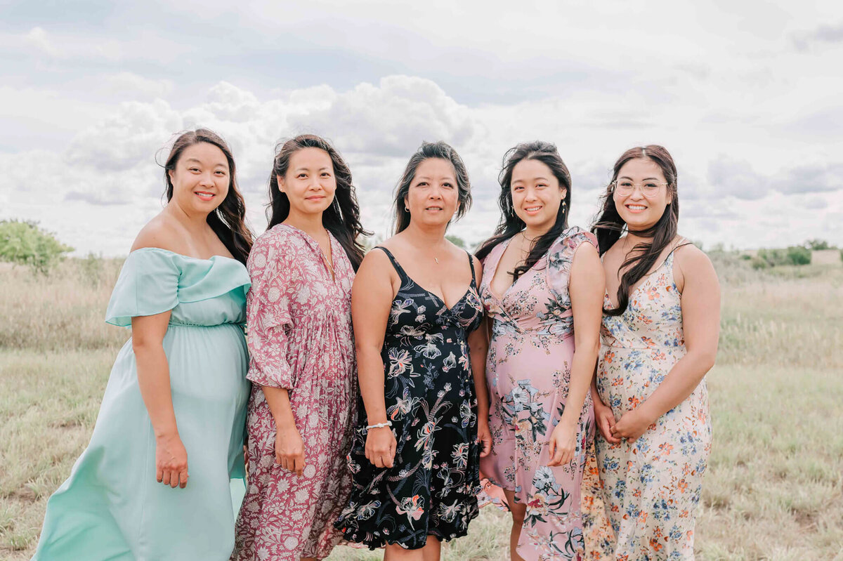 5 older sisters stand together in a field. 