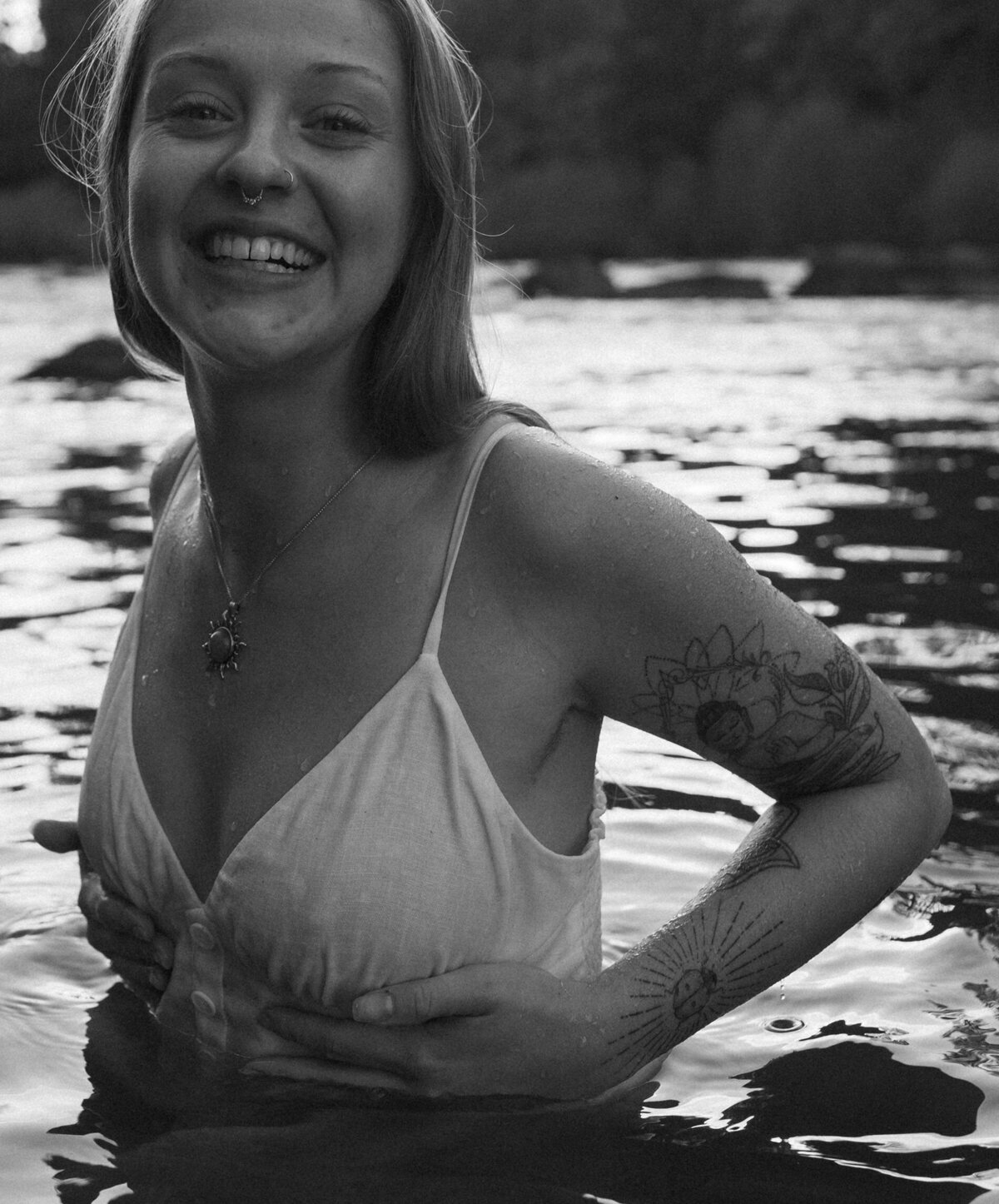 woman in white dress stands in the river while smiling at the camera in Bend, Oregon