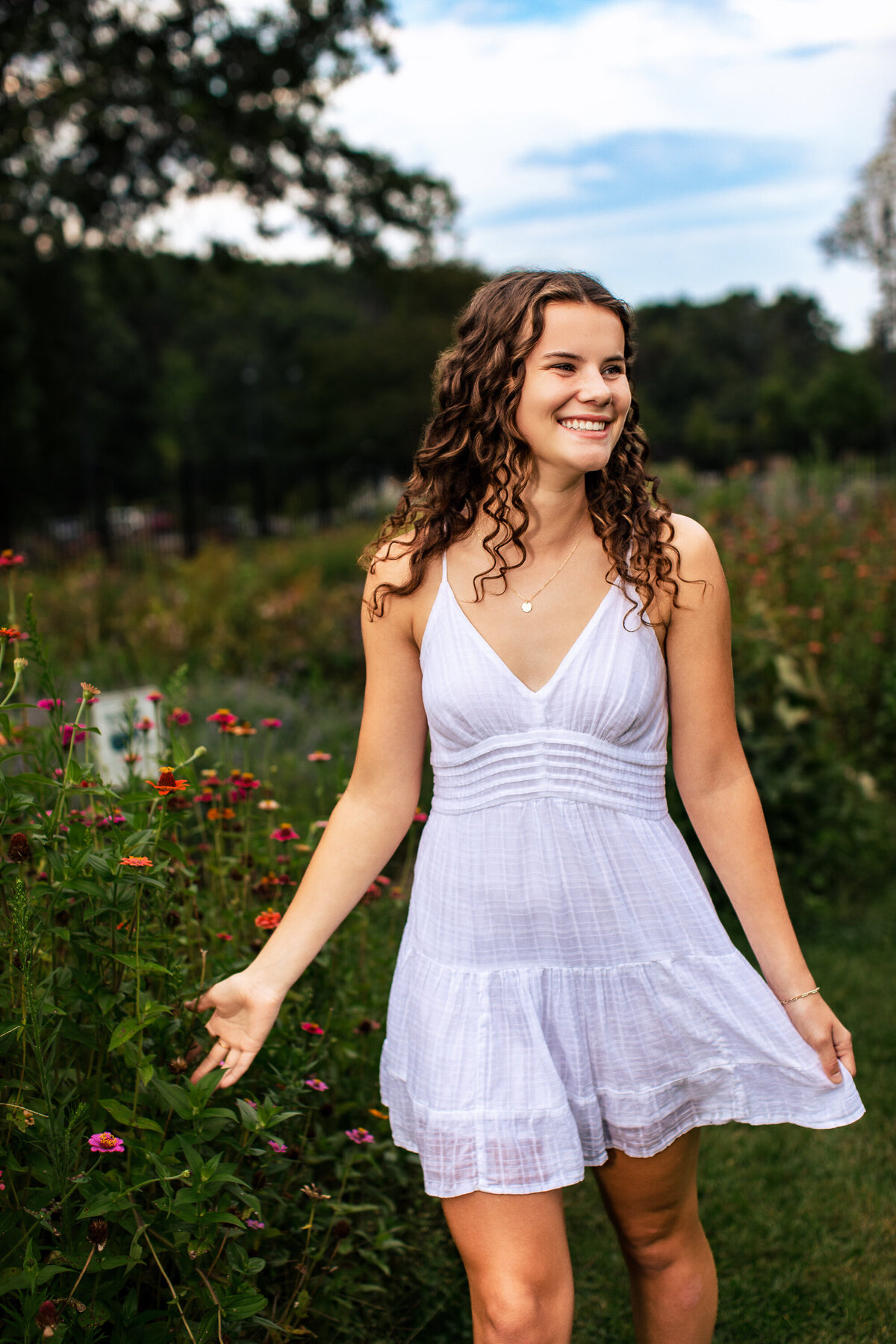 The striking image of a girl wearing a white dress walking through a flower field with her curly hair bouncing catches the eye