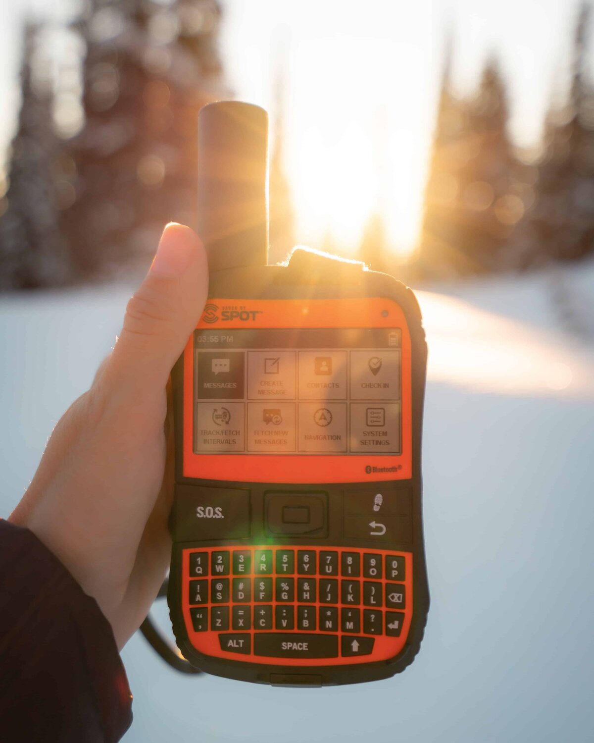 Woman holding an orange SPOT GPS in the snow