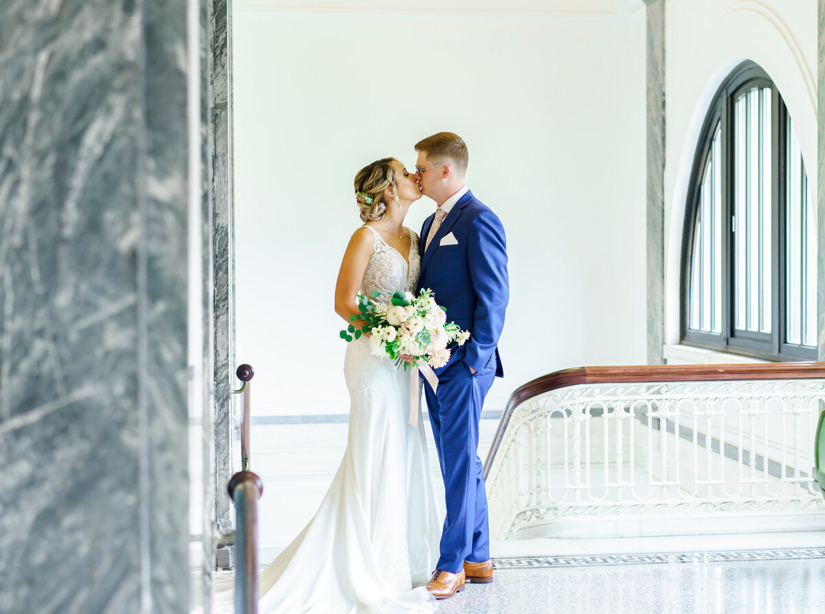 Bride and groom kiss at the top of a staircase at the Columbus Metropolitan Library Main Branch.