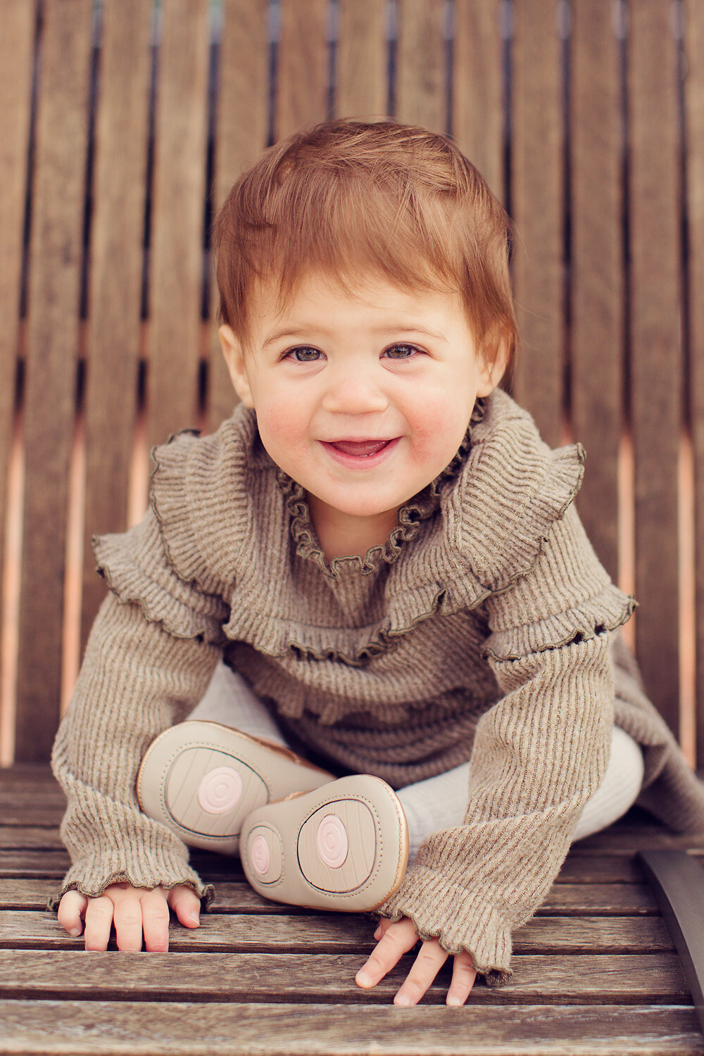 Baby sitting on a bench in Carmel and smiling happily at the camera.