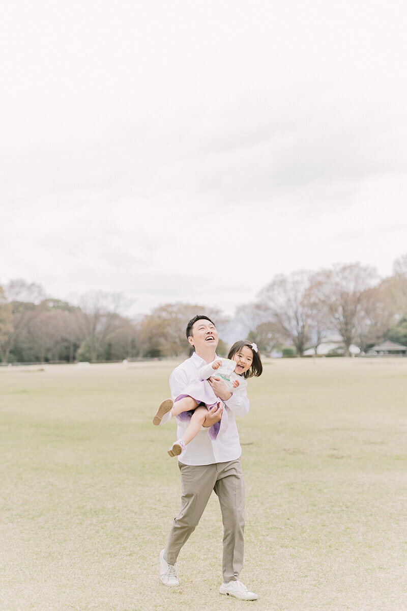 女の子を抱っこして笑っているパパと娘のかわいらしい家族写真。相模原市の公園で撮影。