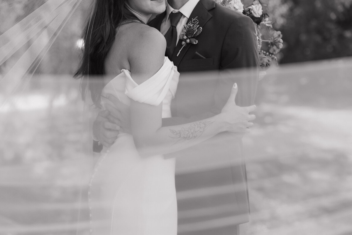 Black-and-white close-up of bride and groom sharing a kiss, captured by Ryann B Photography for a timeless wedding moment.