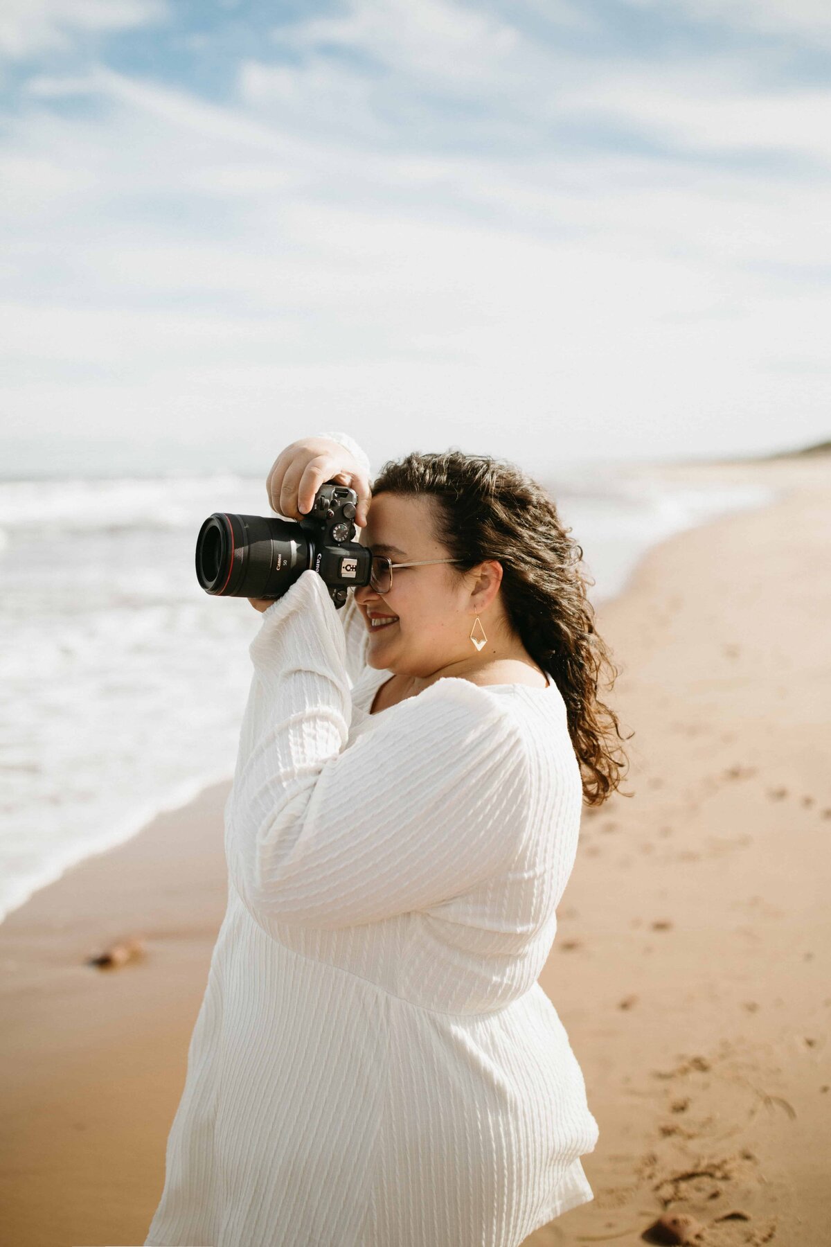 A solo portrait of the side profile of Valerie Doucette, a wedding, engagement, elopement, couples photographer taking a photo of the sea