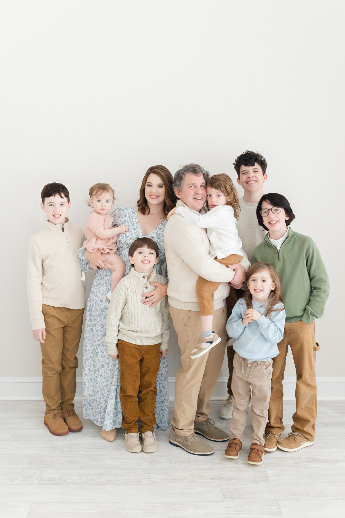 A family with two parents and seven children standing and smiling in our Nova Studio Photography studio