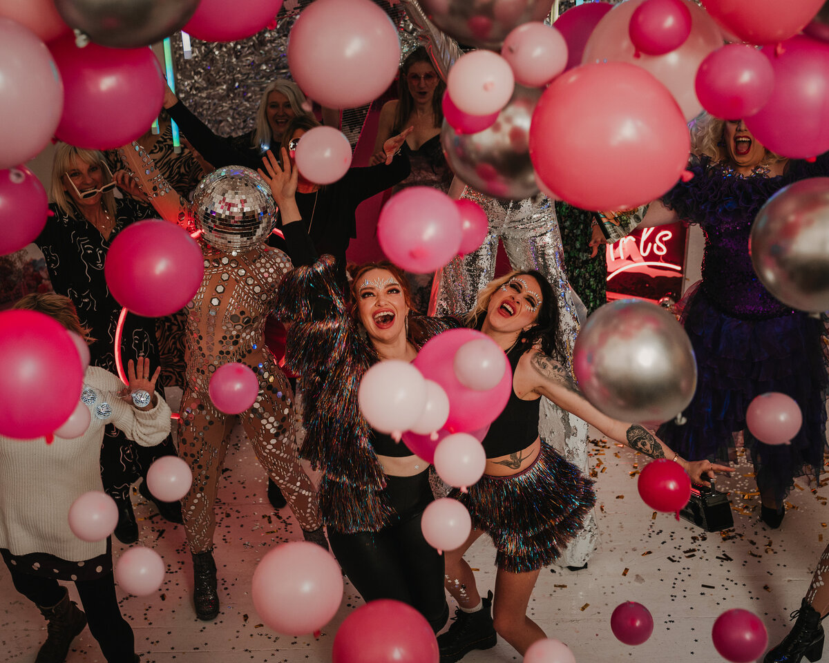 Fun shot of two alternative brides with pink and silver balloons