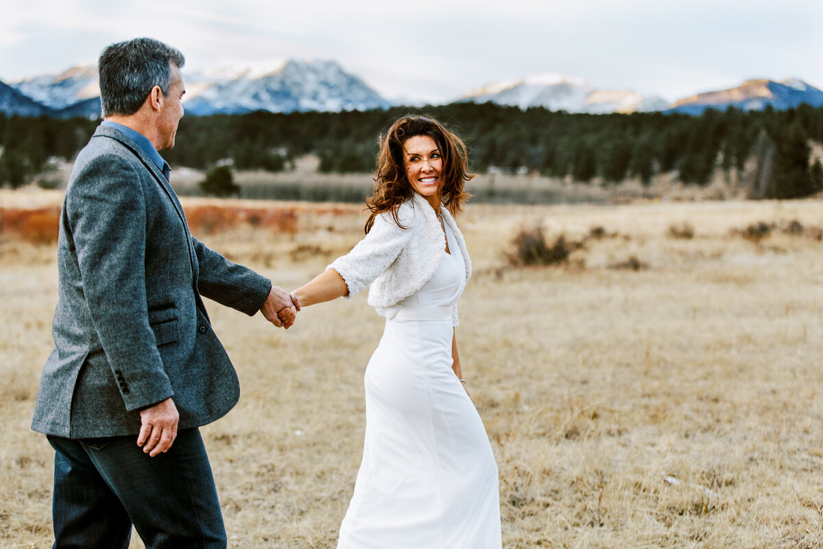 Colorado elopement in Rocky Mountain National Park with bride leading husband through meadow
