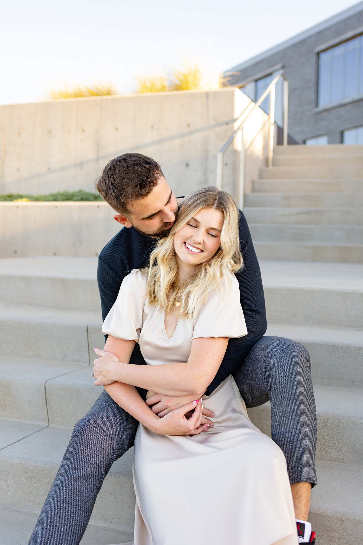 The cute engagement couple share a cute snuggle on the steps of a local college.