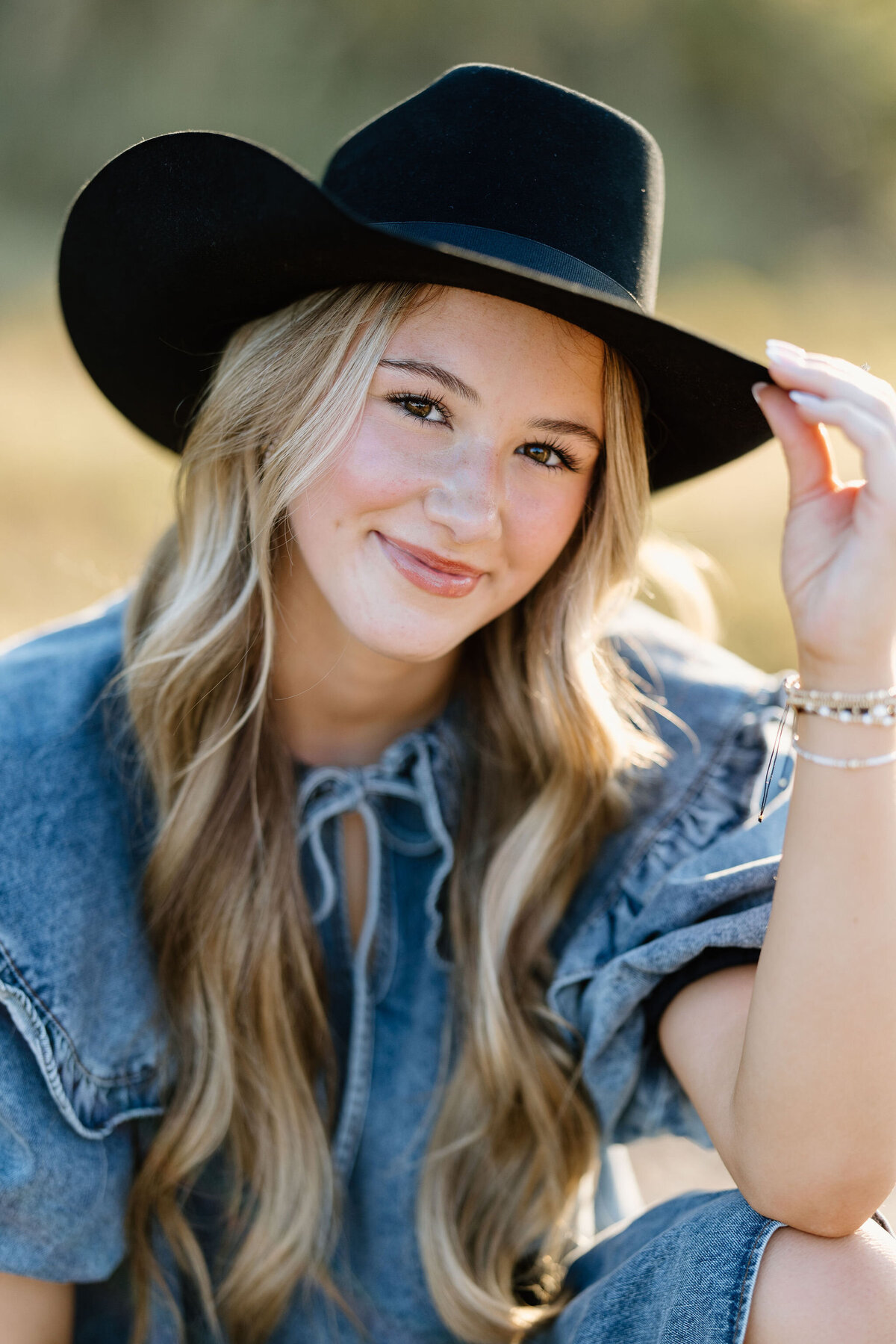 senior photoshoot of senior girl in denim dress and black felt cowboy hat