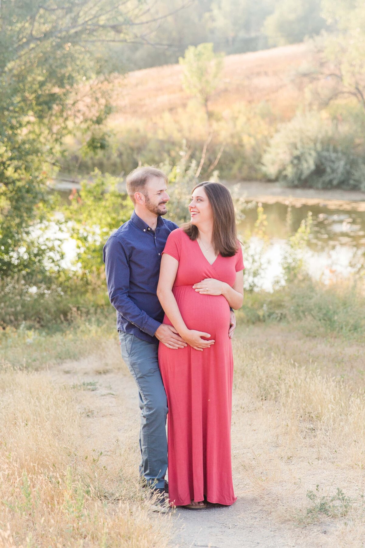 couple laugh while holding baby bump in Superior, Colorado
