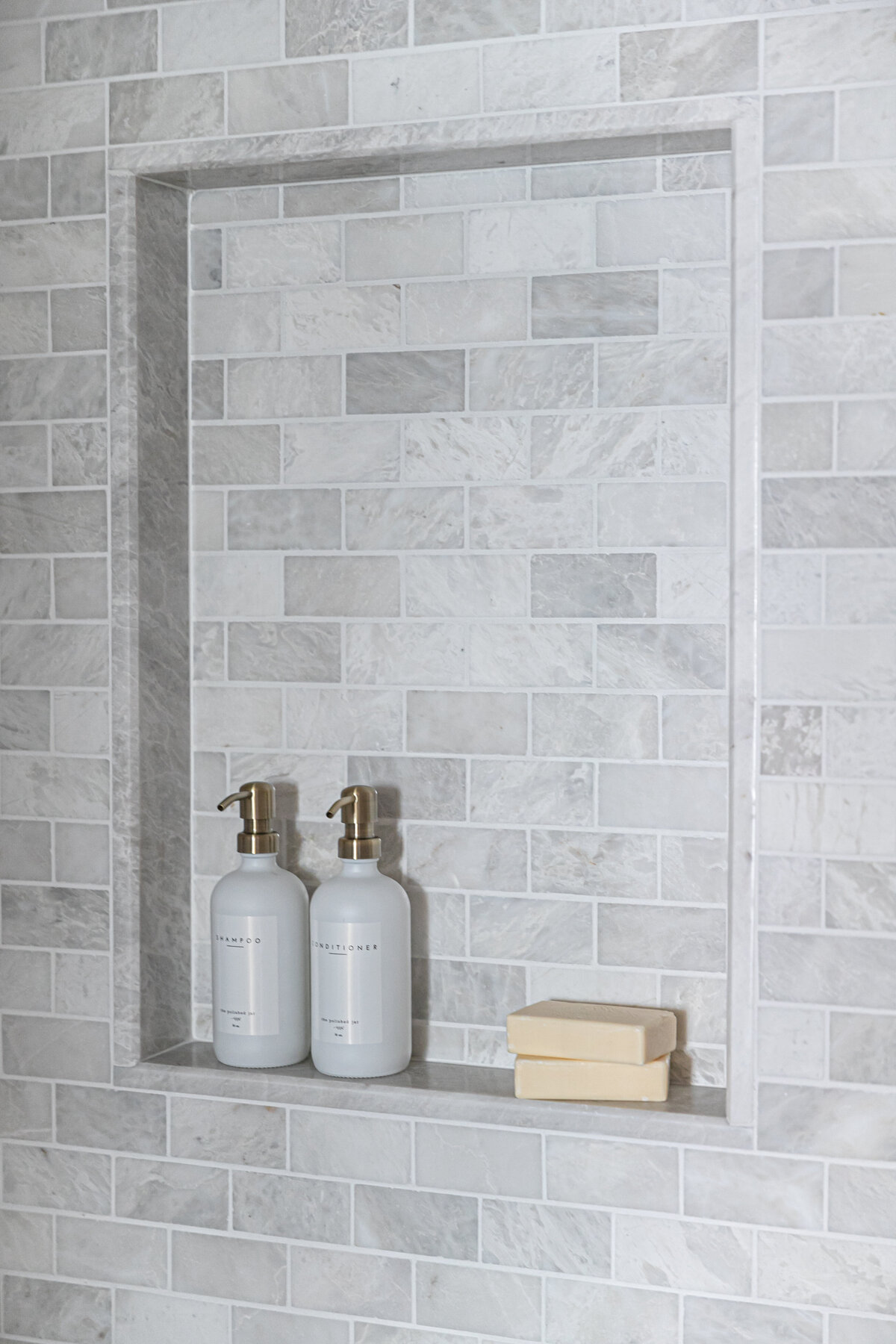 Shower niche with marble subway tile.