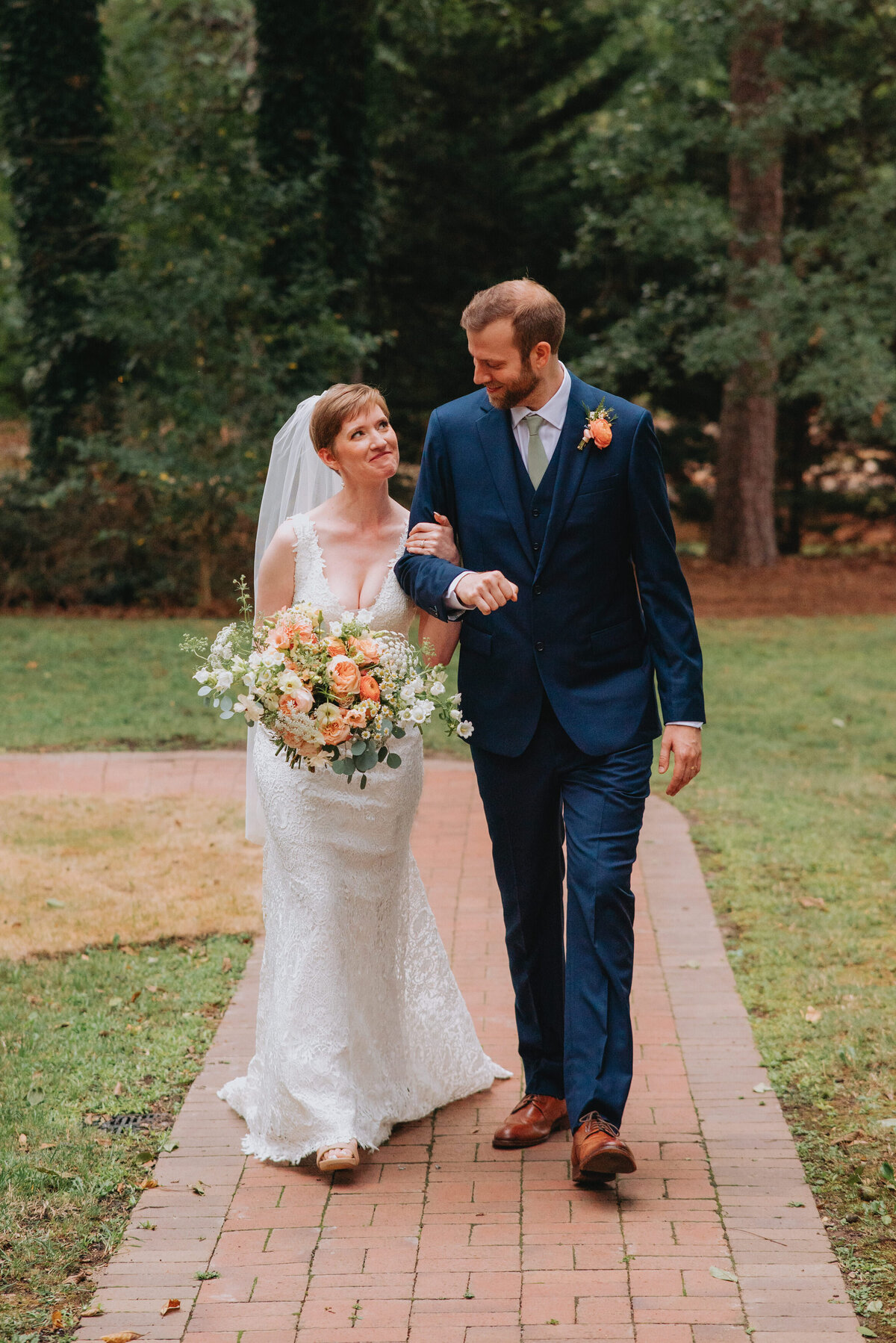 Newlyweds walk hand in hand down a path