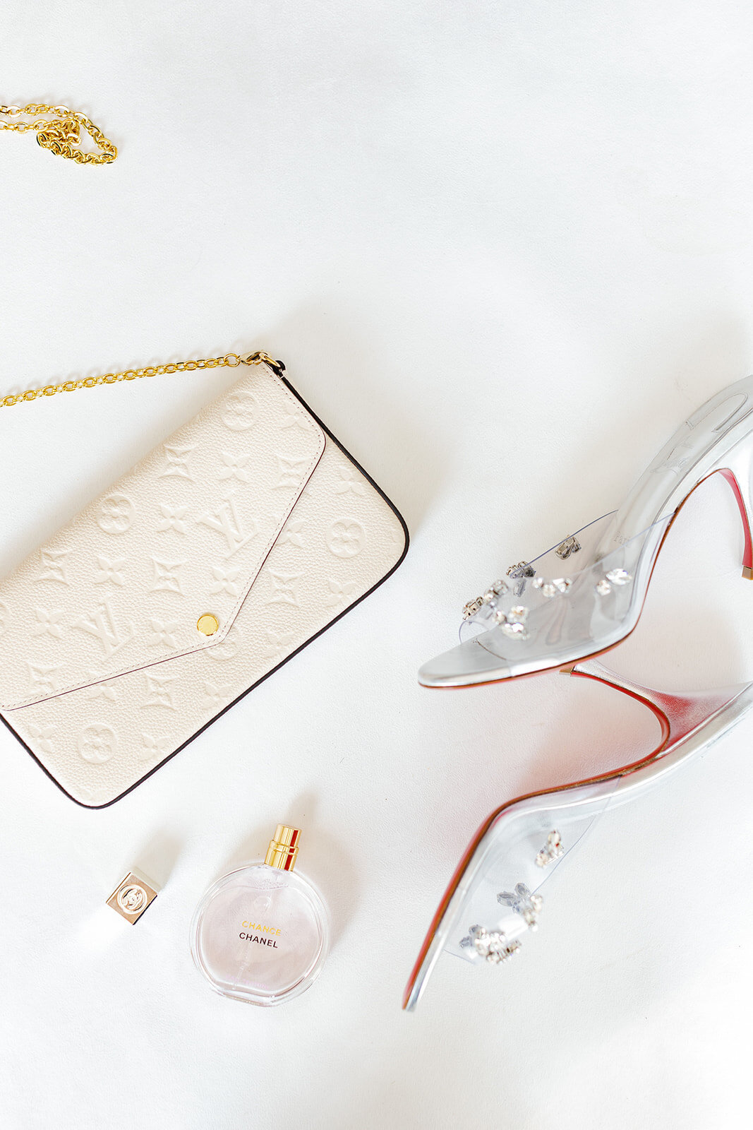 Bride Andressa's luxury bridal accessories, including a Louis Vuitton clutch, perfume, and crystal-embellished heels, styled at Table Key, Islamorada. Photography by Claudia Amalia Wedding Photography.