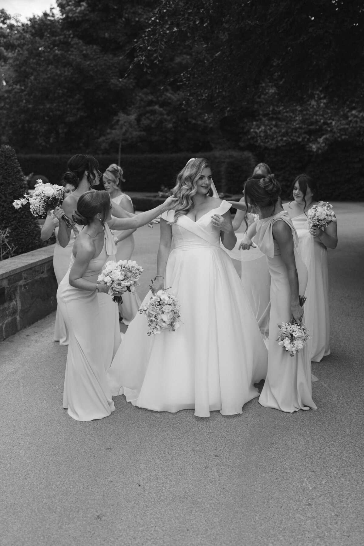 A bridal party gathered around the bride, giving her final touches and making sure she’s ready for her walk down the aisle.