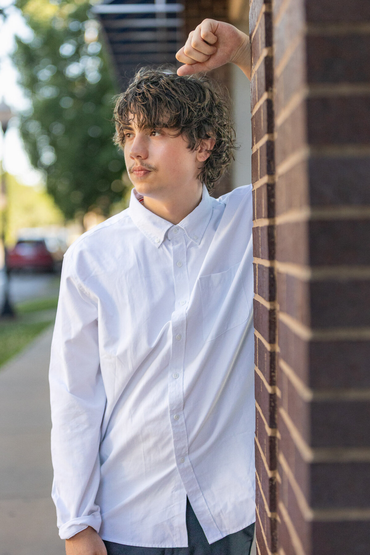 A senior guy leaning against a brick wall in Lawrence, KS