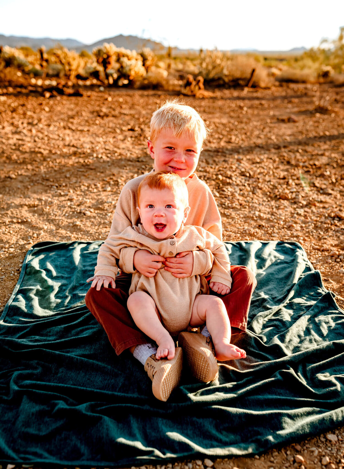 sons hugging and sitting on blanket for family photography session in Arizona during wintertime