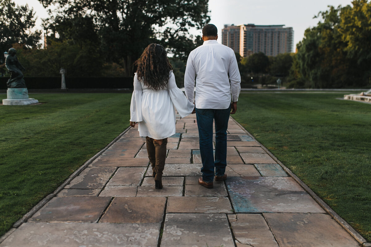 Woman and man hold hands and walk outside.
