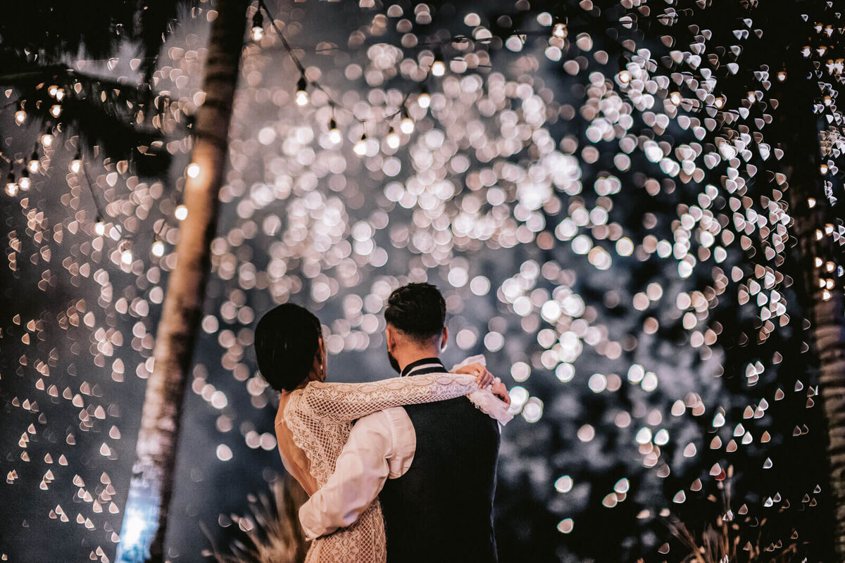 The bride and groom are watching the fireworks at their wedding reception in Bali, Indonesia. Image by Jenny Fu Studio