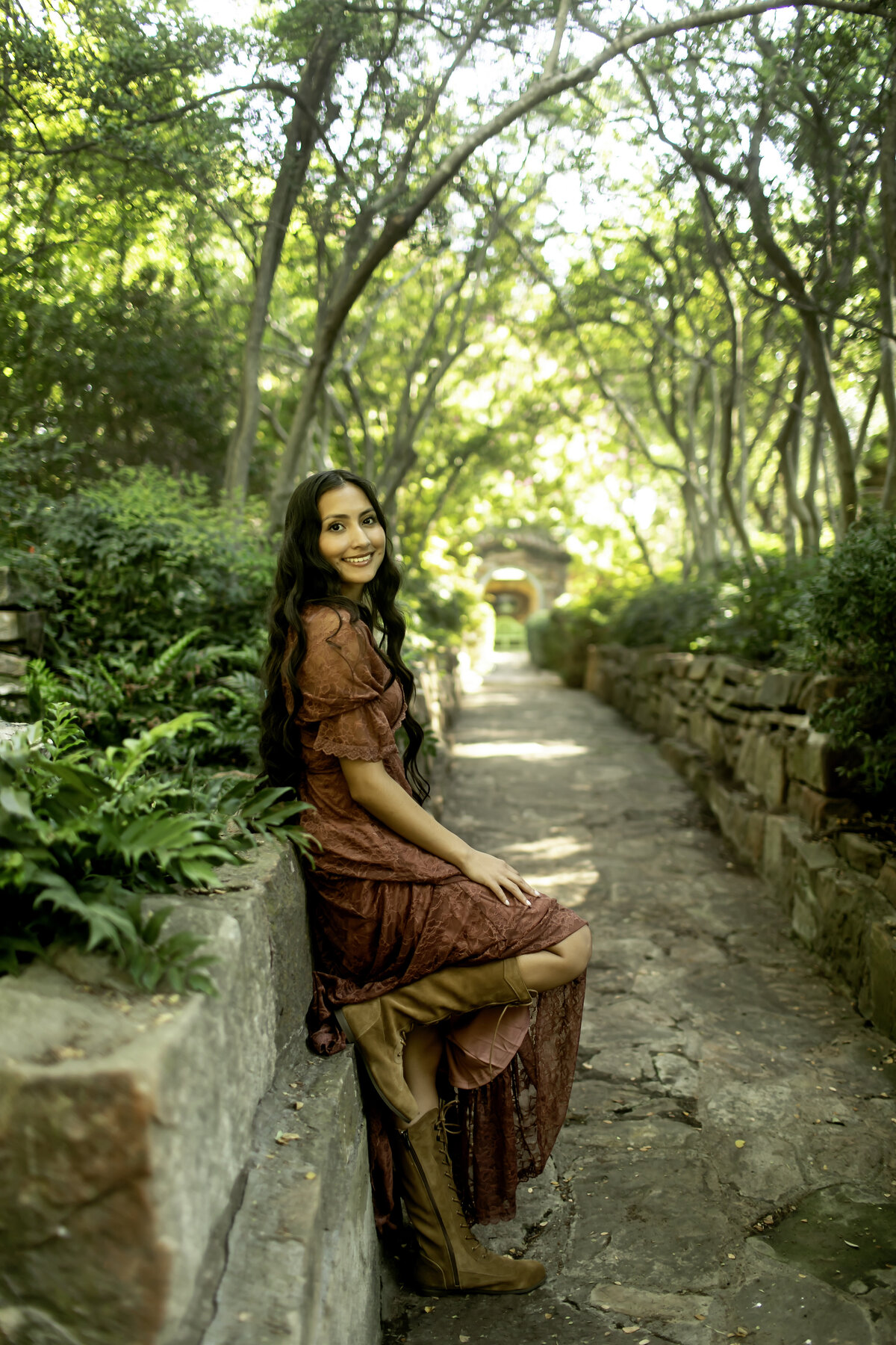A high school senior enjoying a peaceful moment among the blooming flowers and trees of Chandor Gardens, Weatherford, TX, as they reflect on their academic journey.