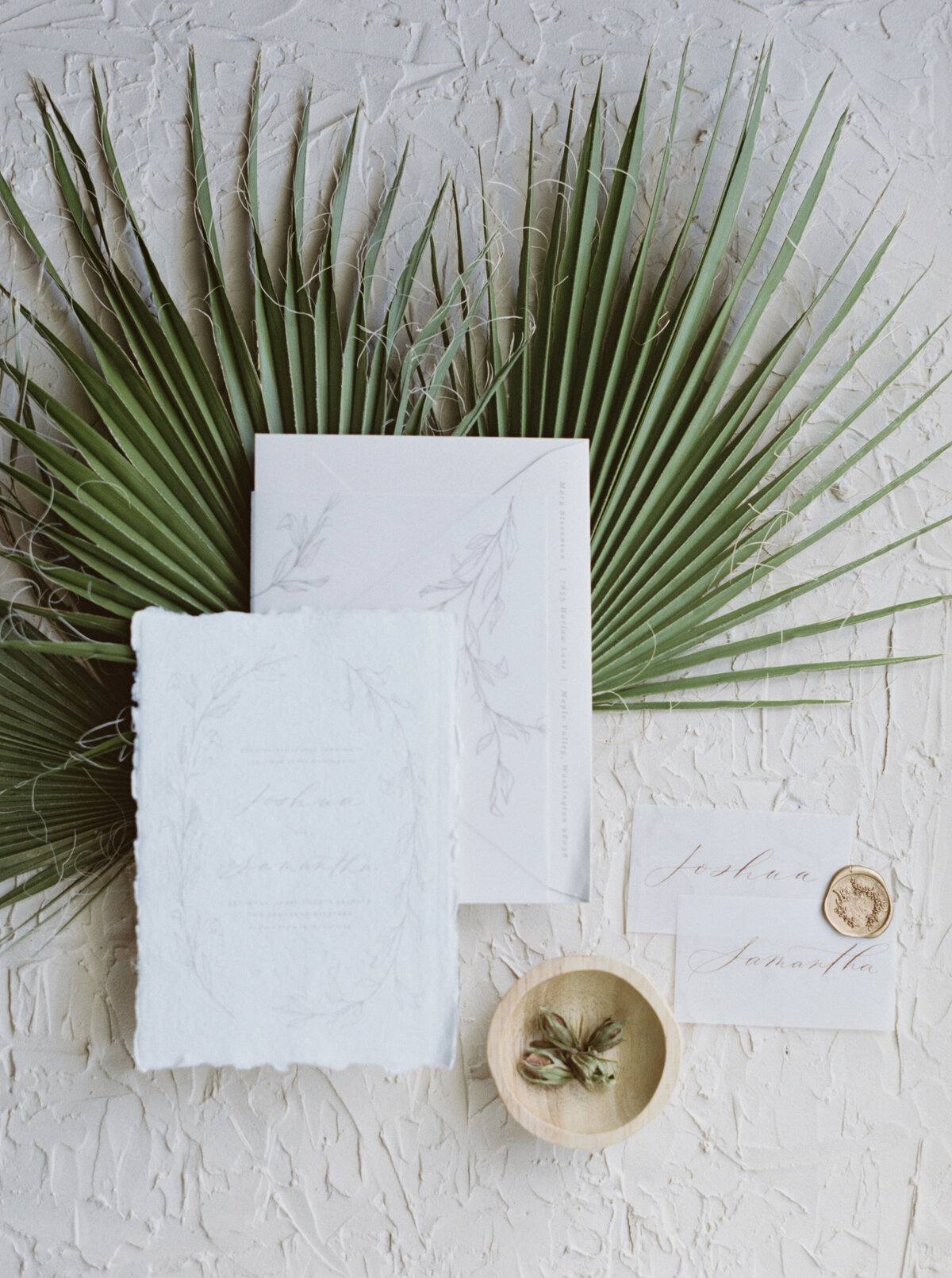 Fancy paper and stuff flatlay on a green palm leaf.