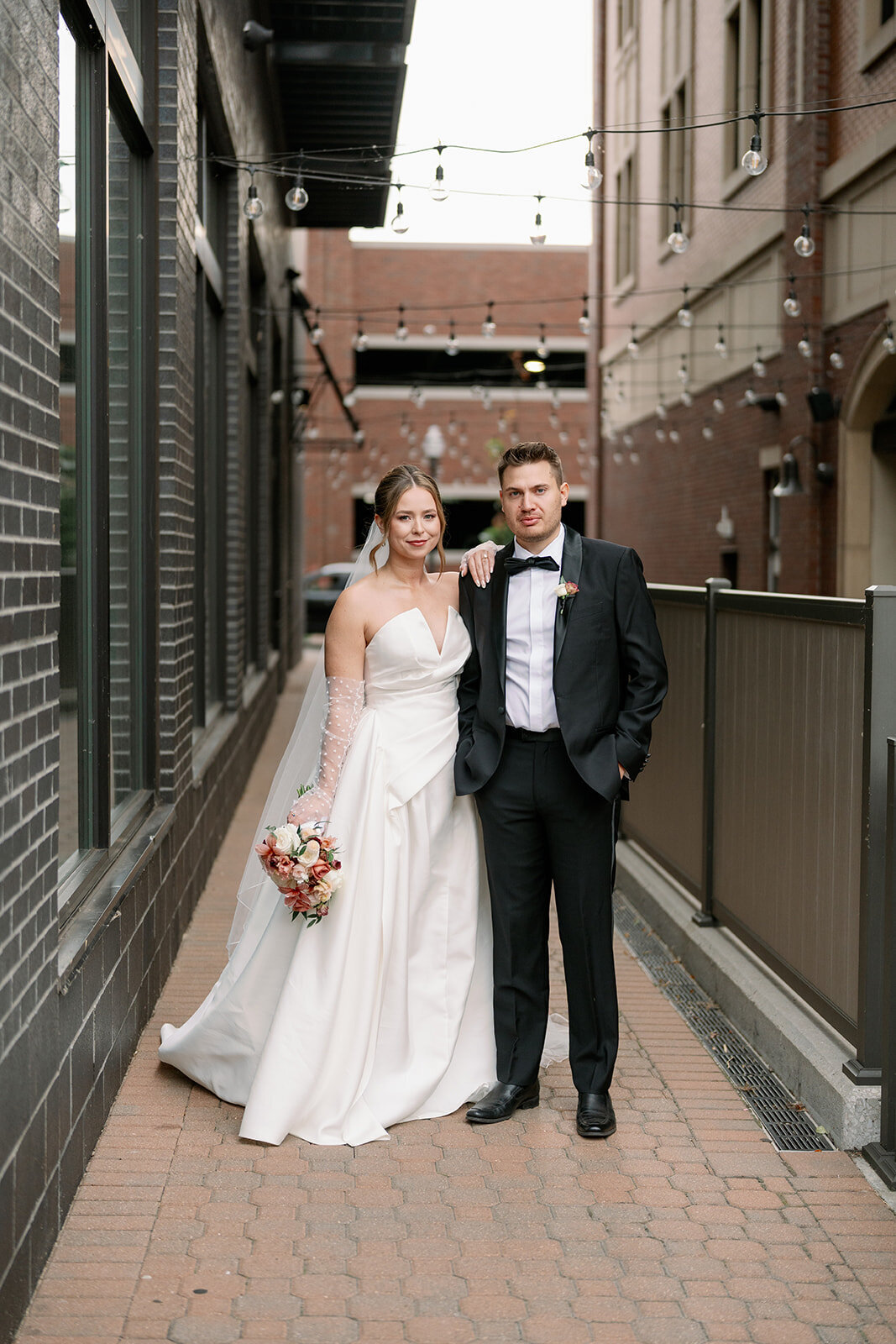 Black tie wedding couple posing outside Boatwerks Waterfront Venue in Holland Michigan with elegant timeless photography.