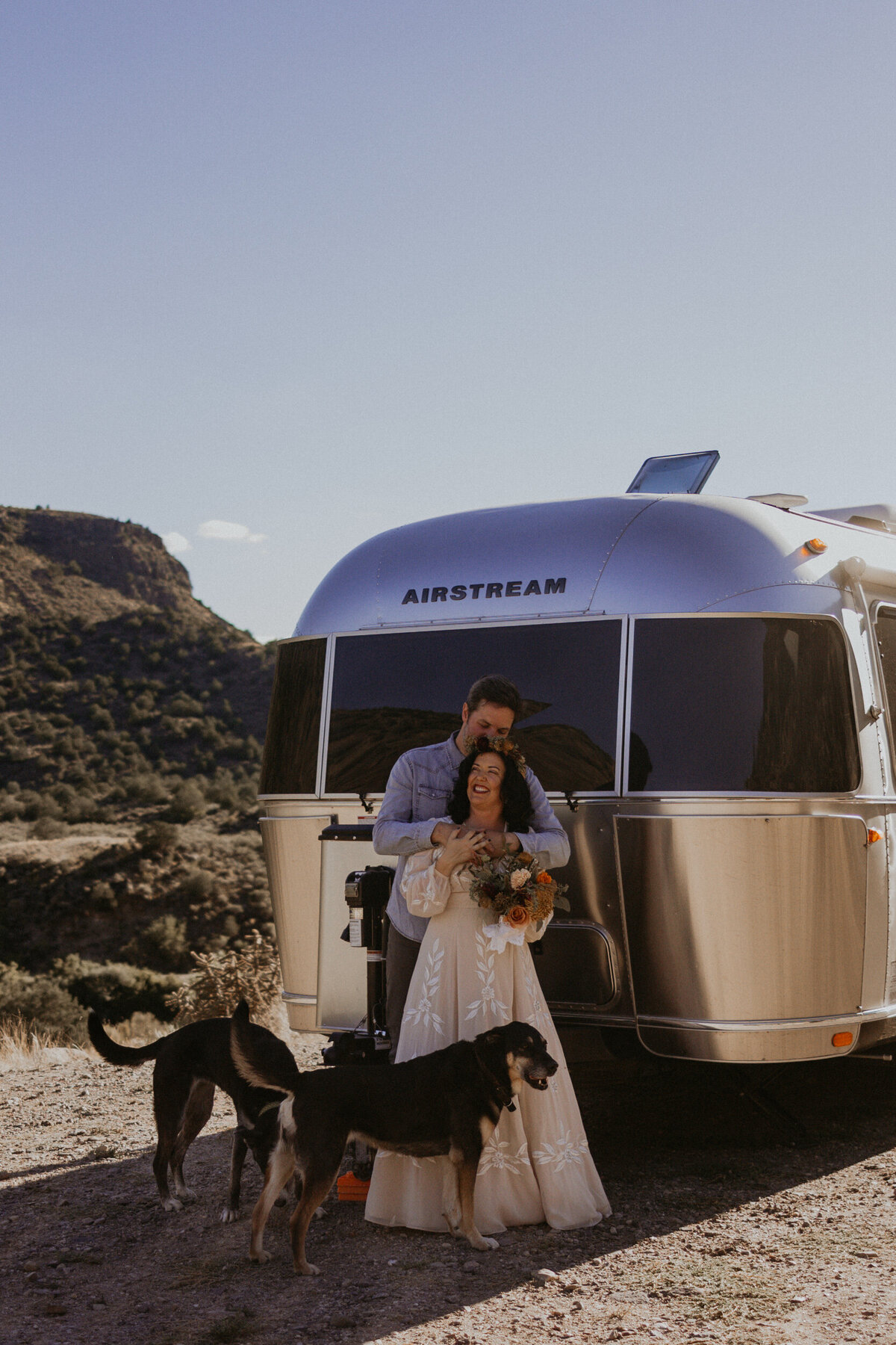 bride and groom with their two dogs and airstream camper